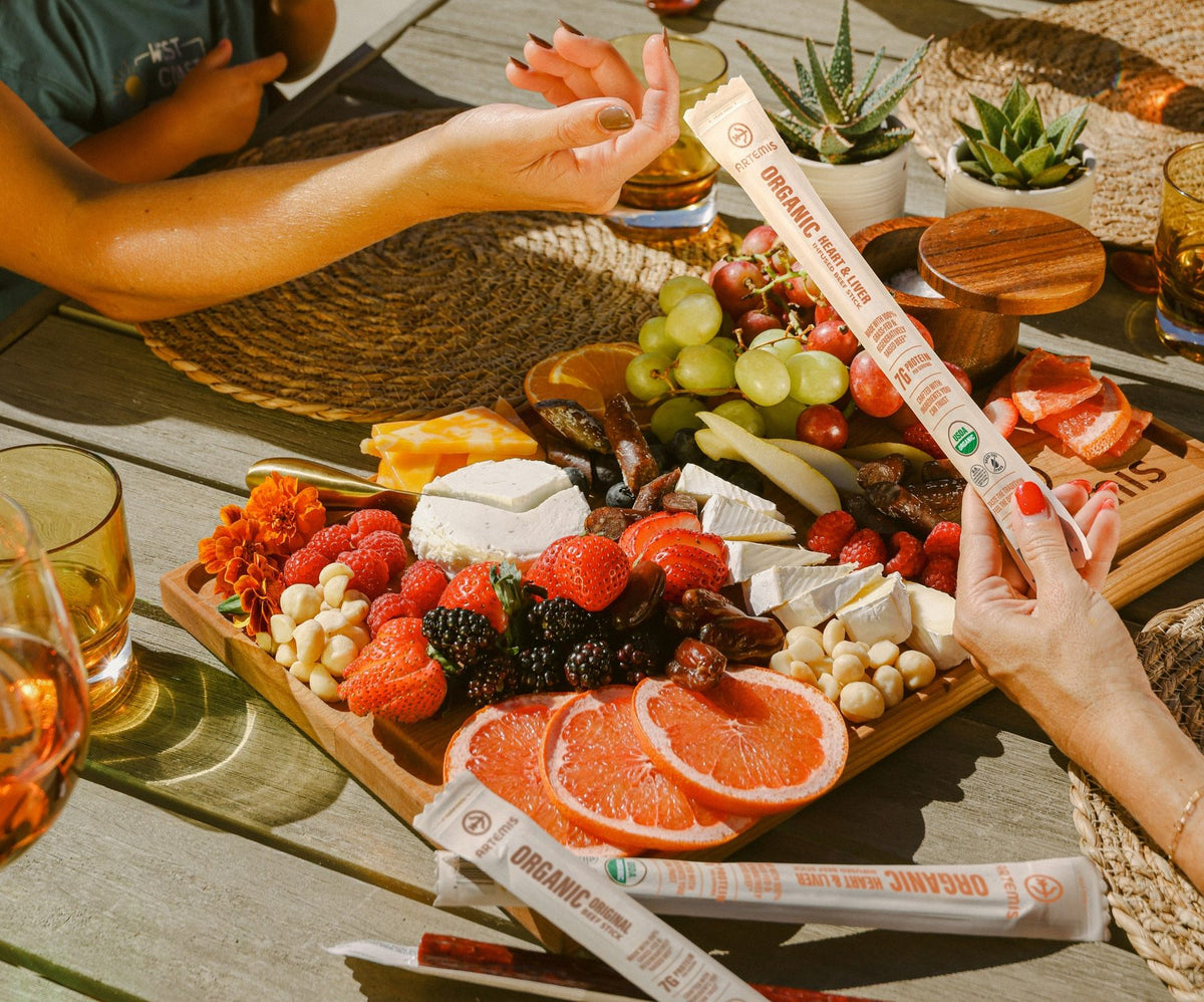 Two people share Artemis beef sticks over a charcuterie board.