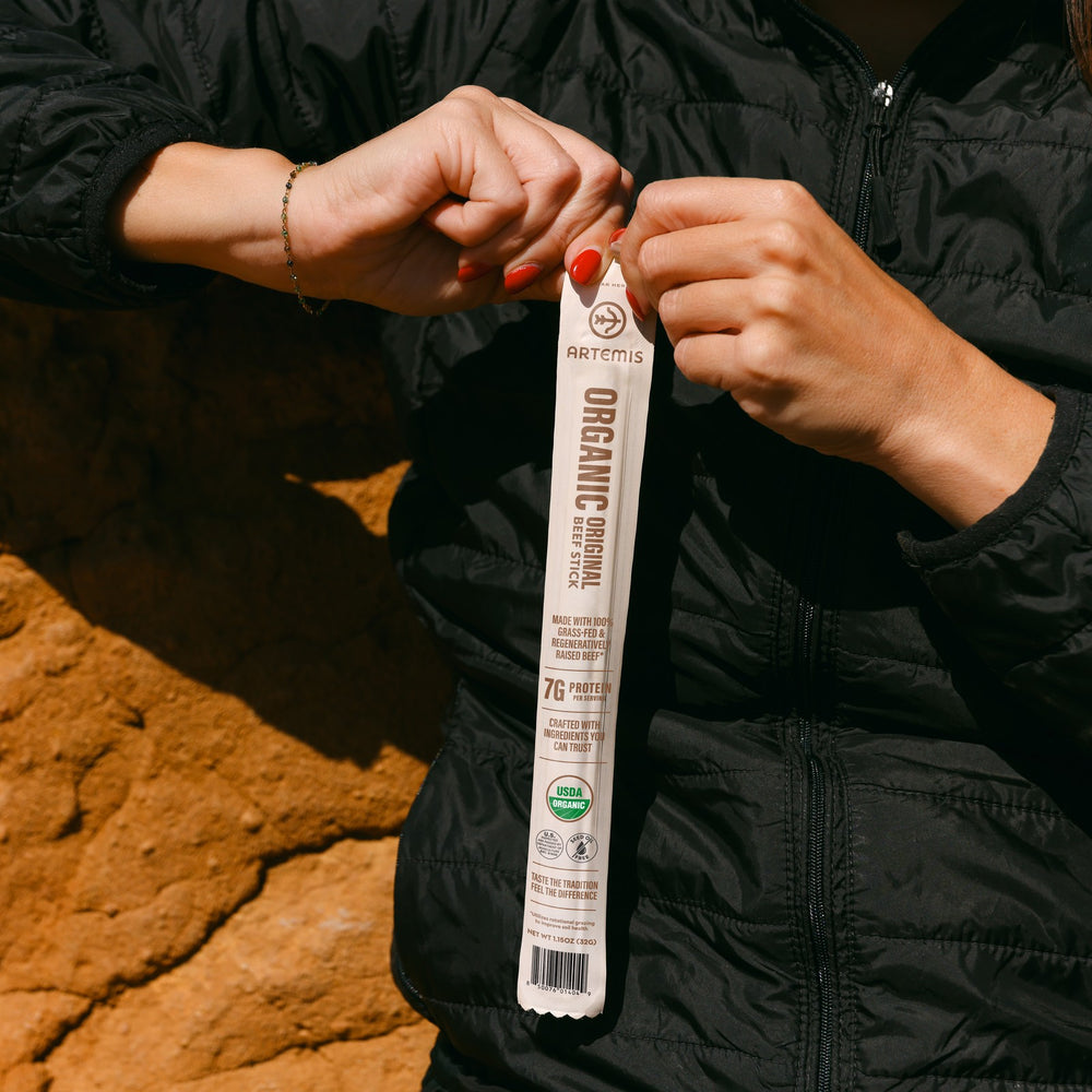 Organic Original Beef Stick held in two hands against a red rock wall