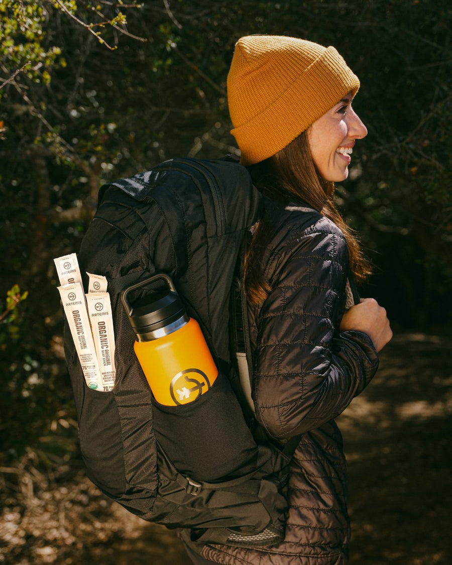 Hiker in an orange beanie with Artemis Organic Original beef sticks and an orange bottle in her backpack